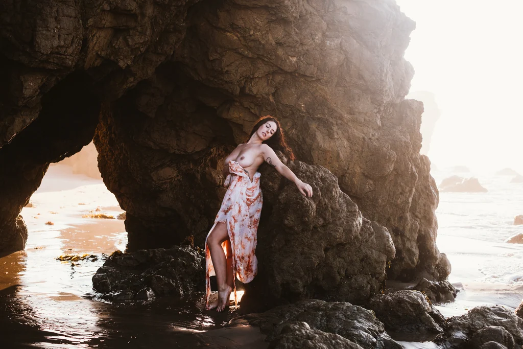Figure framed within a sea arch at golden hour on the Malibu coast