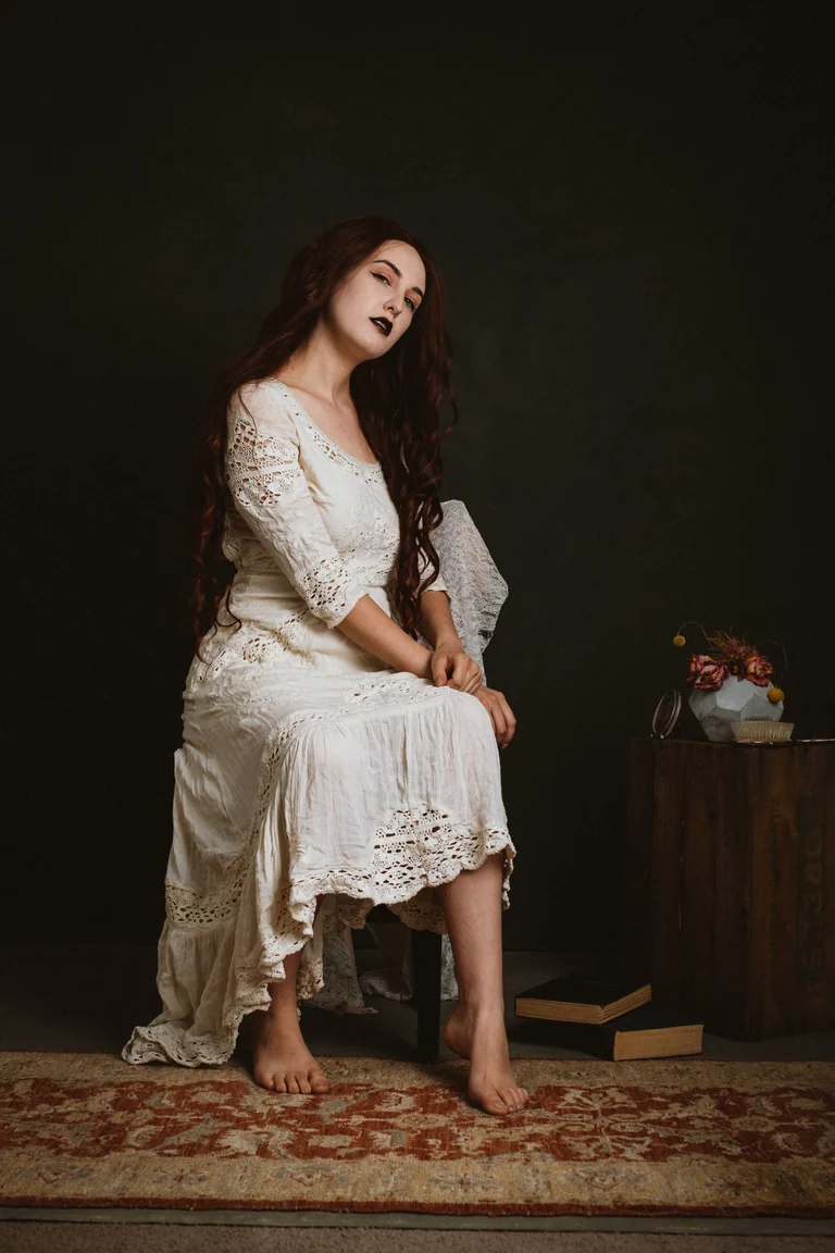 Woman in a vintage lace dress among antique props