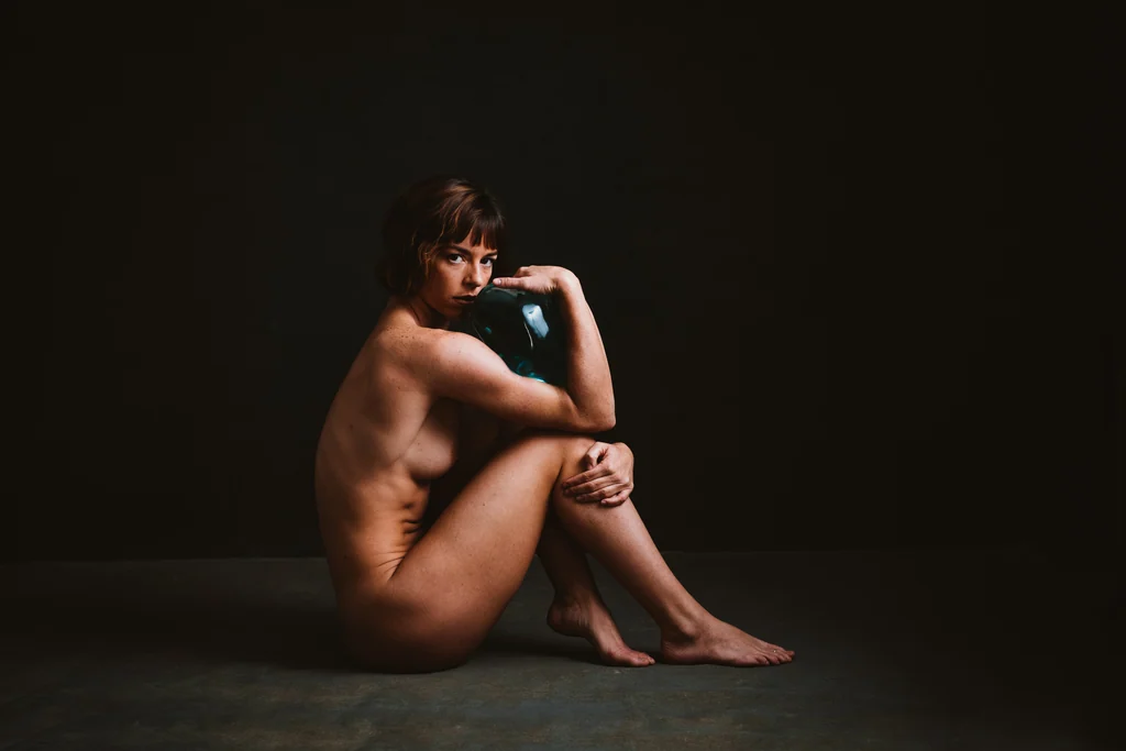 Studio study, seated figure holding a small glass vessel, direct gaze